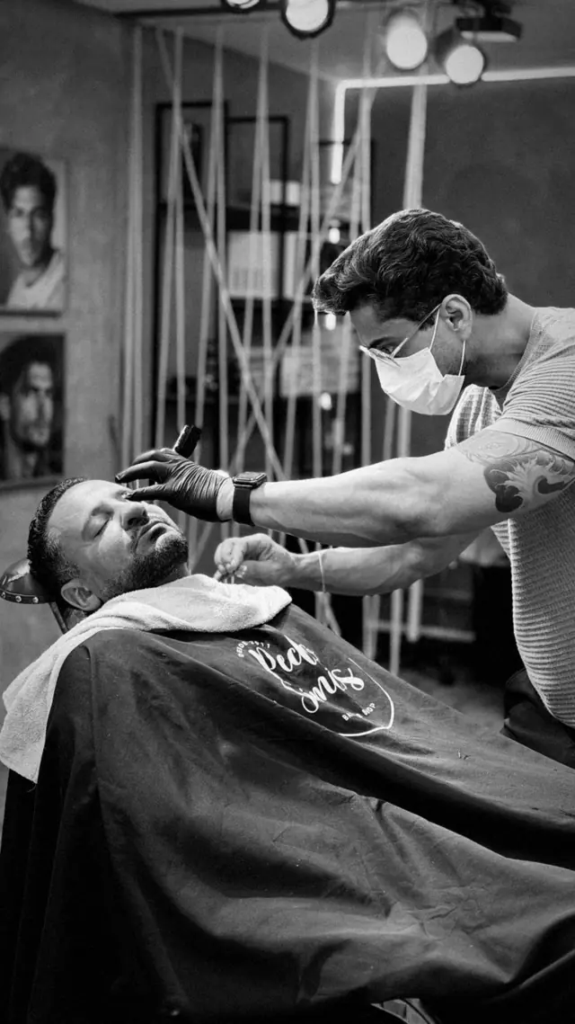 Barbeiro fazendo a barba de um cliente